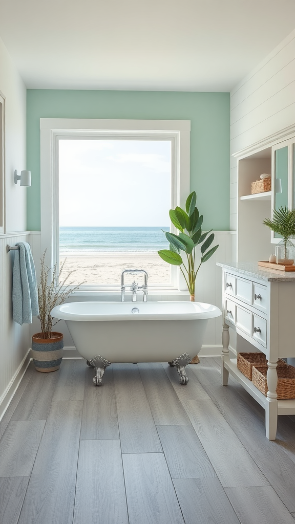 Coastal bathroom with a view of the beach, featuring a freestanding bathtub and mint green walls.