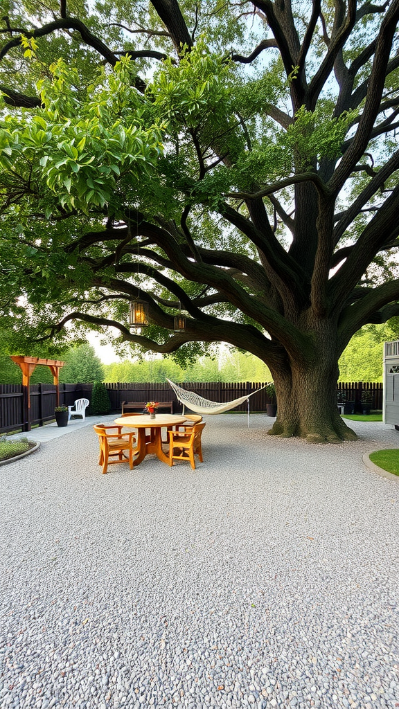 Gravel patio with a large tree providing shade, featuring a wooden table and chairs.