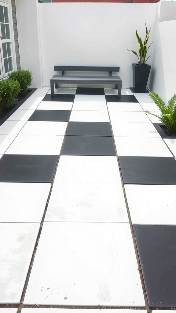 Minimalist black and white paver patio with large tiles arranged in a checkerboard pattern, featuring a bench and potted plants.