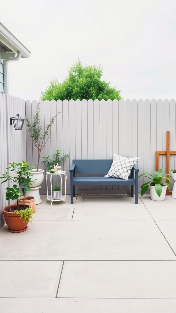 A minimalist outdoor seating nook featuring a blue bench, potted plants, and a light gray fence.